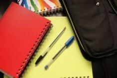 photo of spiral bound notebooks in various colours scattered on a desk with 2 pens